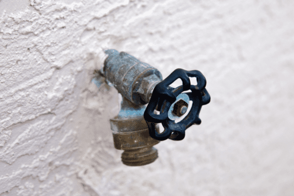 A hose bib style backflow preventer on an outdoor faucet.