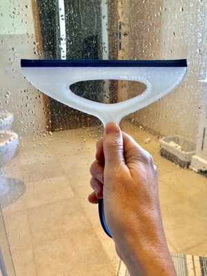A squeegee removes moisture from a shower.