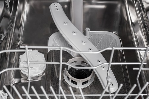 The spinning arm with nozzles inside an open dishwasher.