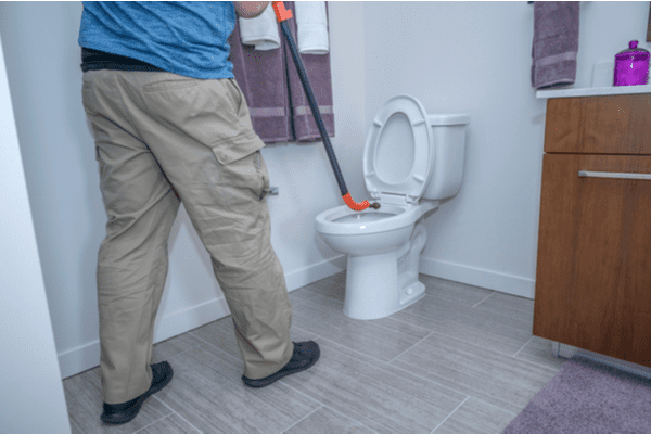 A homeowner uses a toilet auger to snake his toilet.