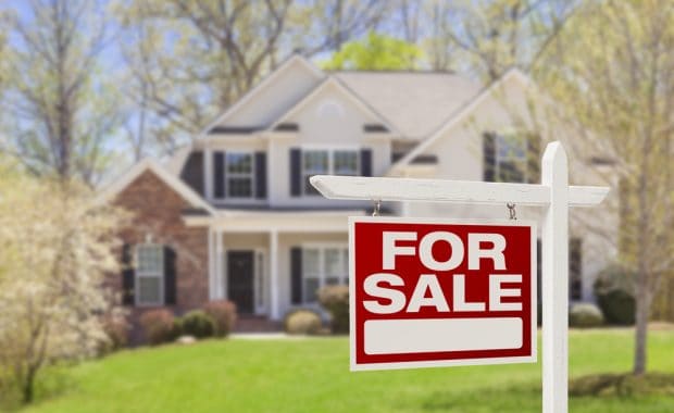 A house with a "for sale" sign out front.