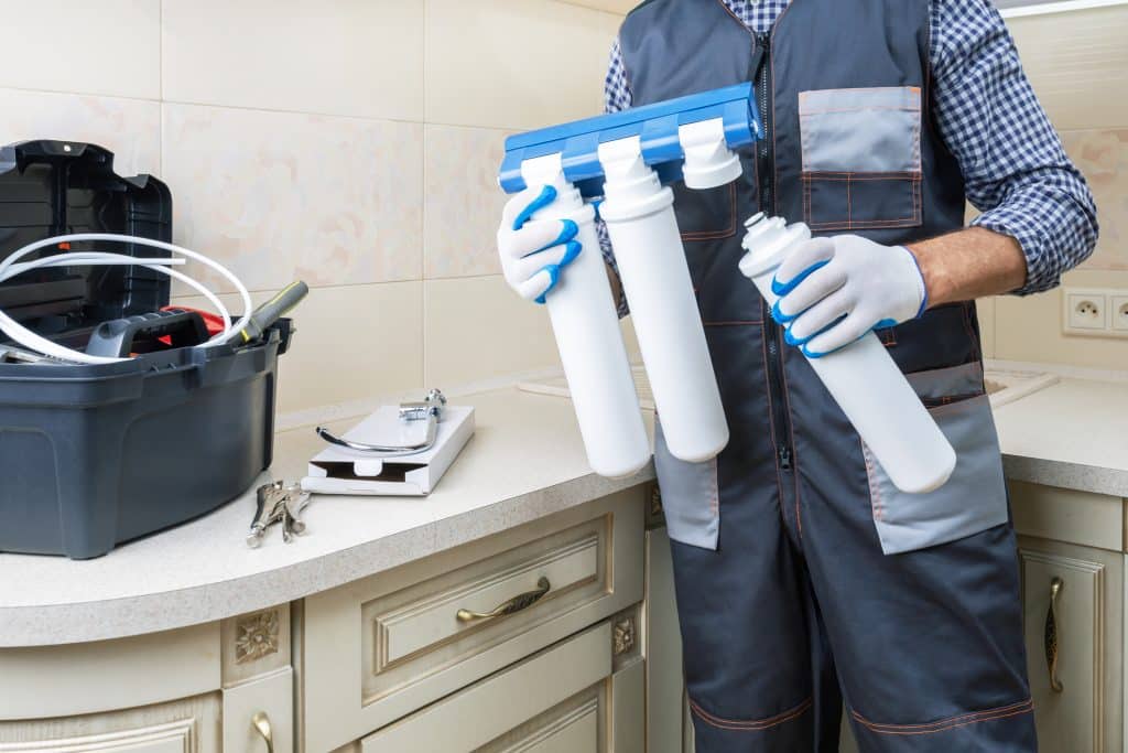 Plumber installing or repairing water filtration systems