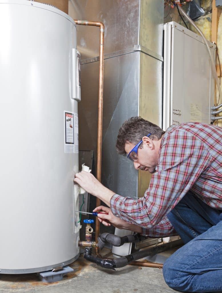 A plumber is performing plumbing maintenance on a residential water heater.