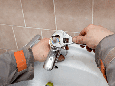 A homeowner removes a faucet cartridge to fix a leak.