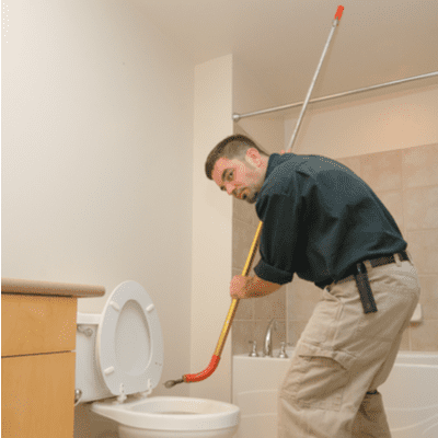 A homeowner uses a toilet auger to unclog his toilet.