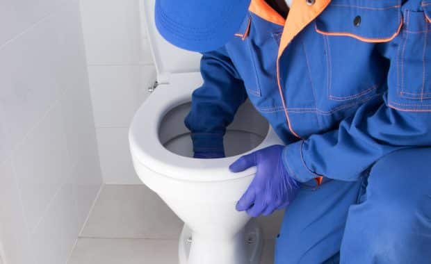 A man is removing a toilet clogs blockage."