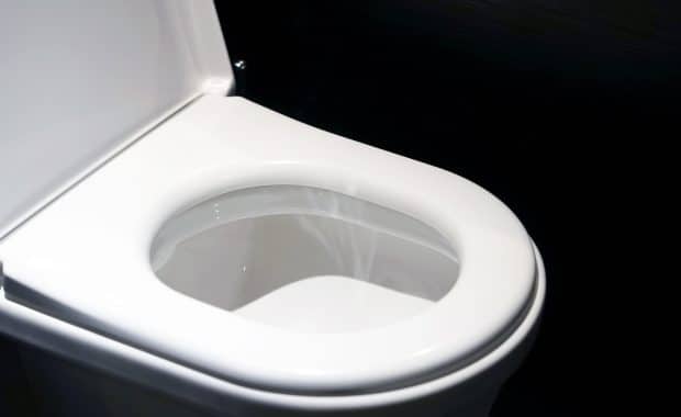 White toilet with a black background; low-flow toilets