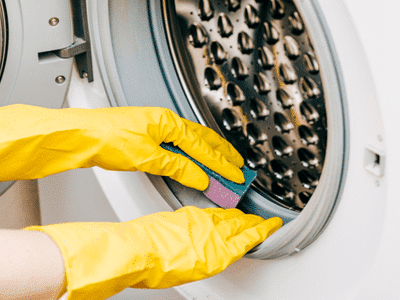 A woman cleans her washing machine door gasket.