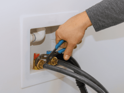 A plumber installs new laundry hook ups.