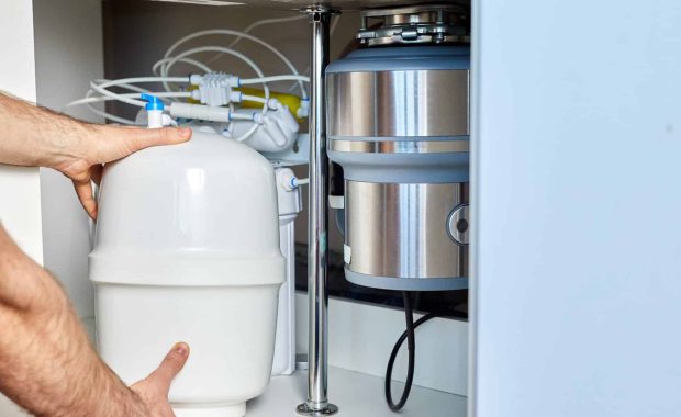 The plumber installs a reverse osmosis equipment as part of the under-sink water filtration systems.