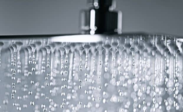 Close-up of water pressure flowing from a showerhead in a bathroom.