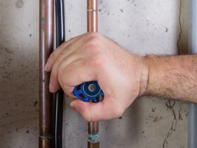 A hand turning a water shut of valve