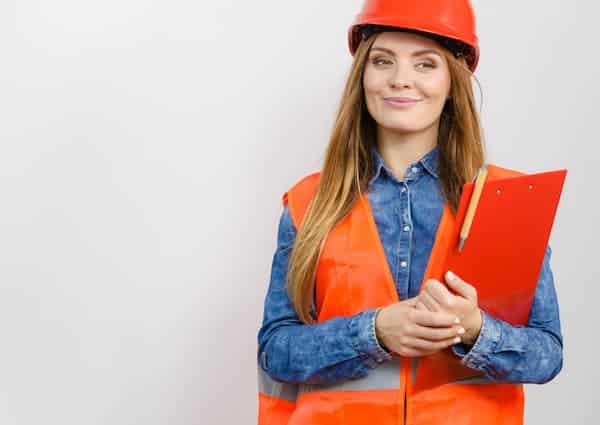 Female construction foreman in orange hardhat and vest with clipboard