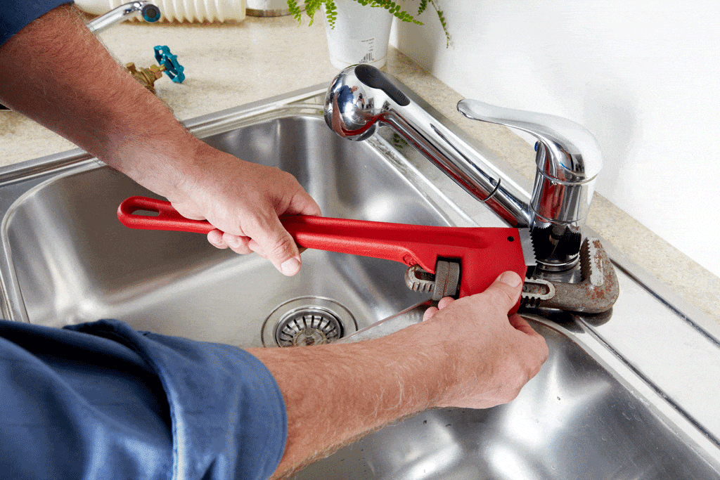 man using red wrench to fix ktichen sink emergency plumbing serivce dallas tx carrollton tx frisco tx