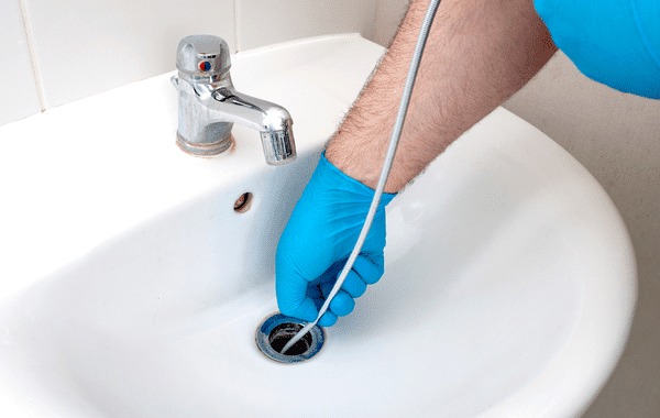 Using a plumber's snake on a bathroom sink clog.