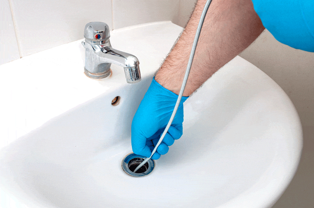 plumber wearing blue gloves sticking something down drain emergency plumbing service dallas tx frisco tx carrollton tx