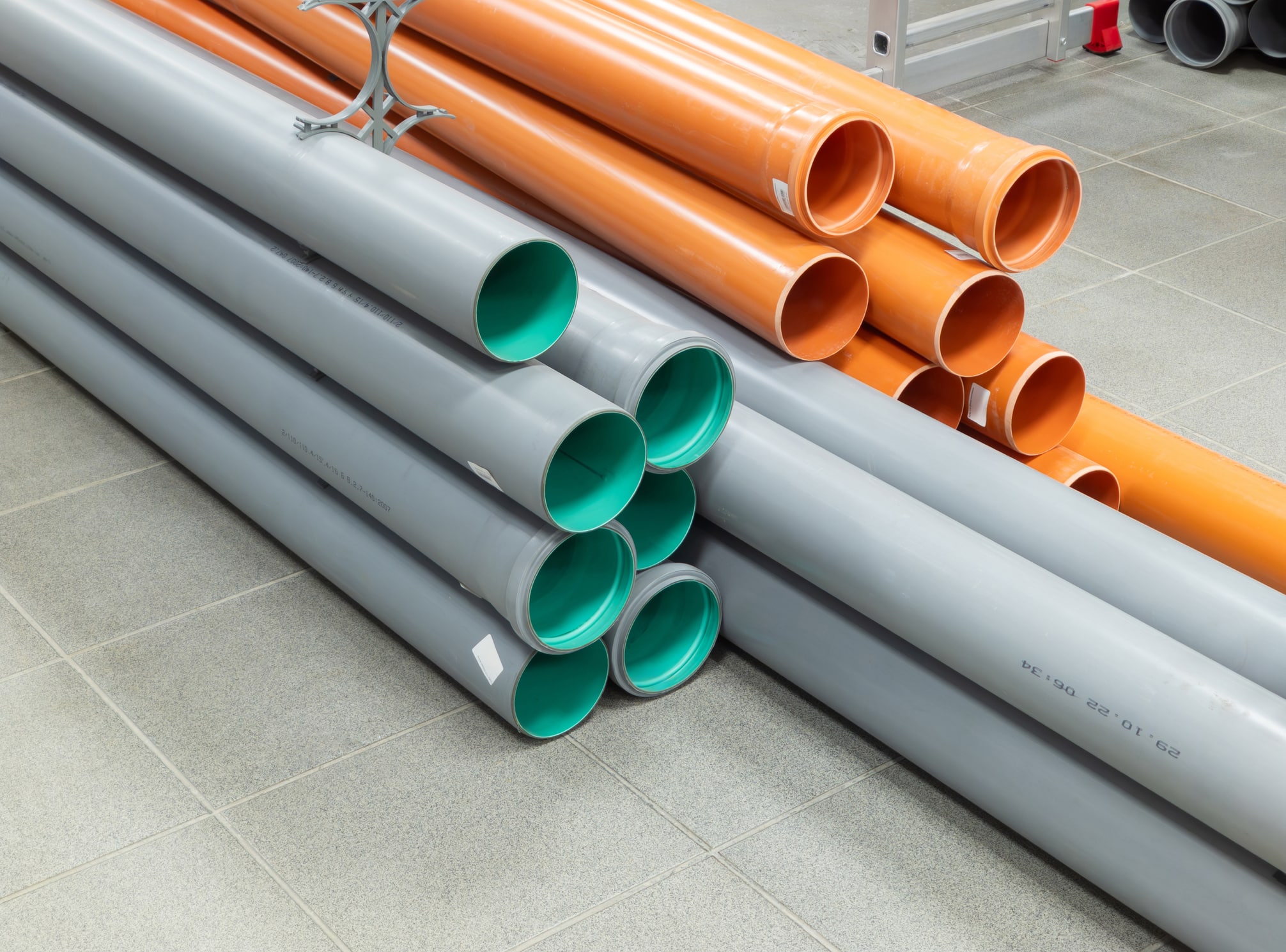 PVC plastic pipes and tubes stacked in warehouse. Choosing a sewage pipe from pipes store and preparing for sewer installation.