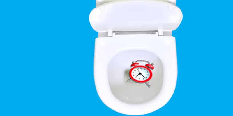Clock in toilet against blue background